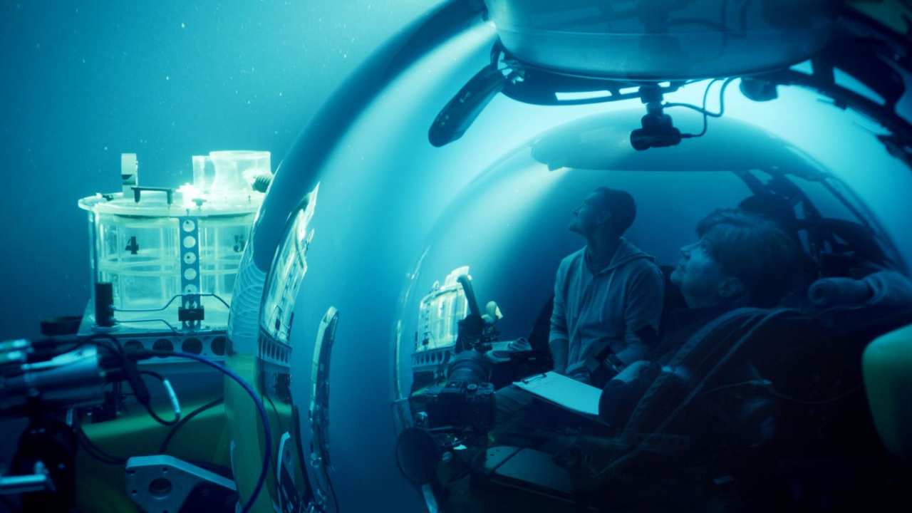two people underwater in a glass vessel